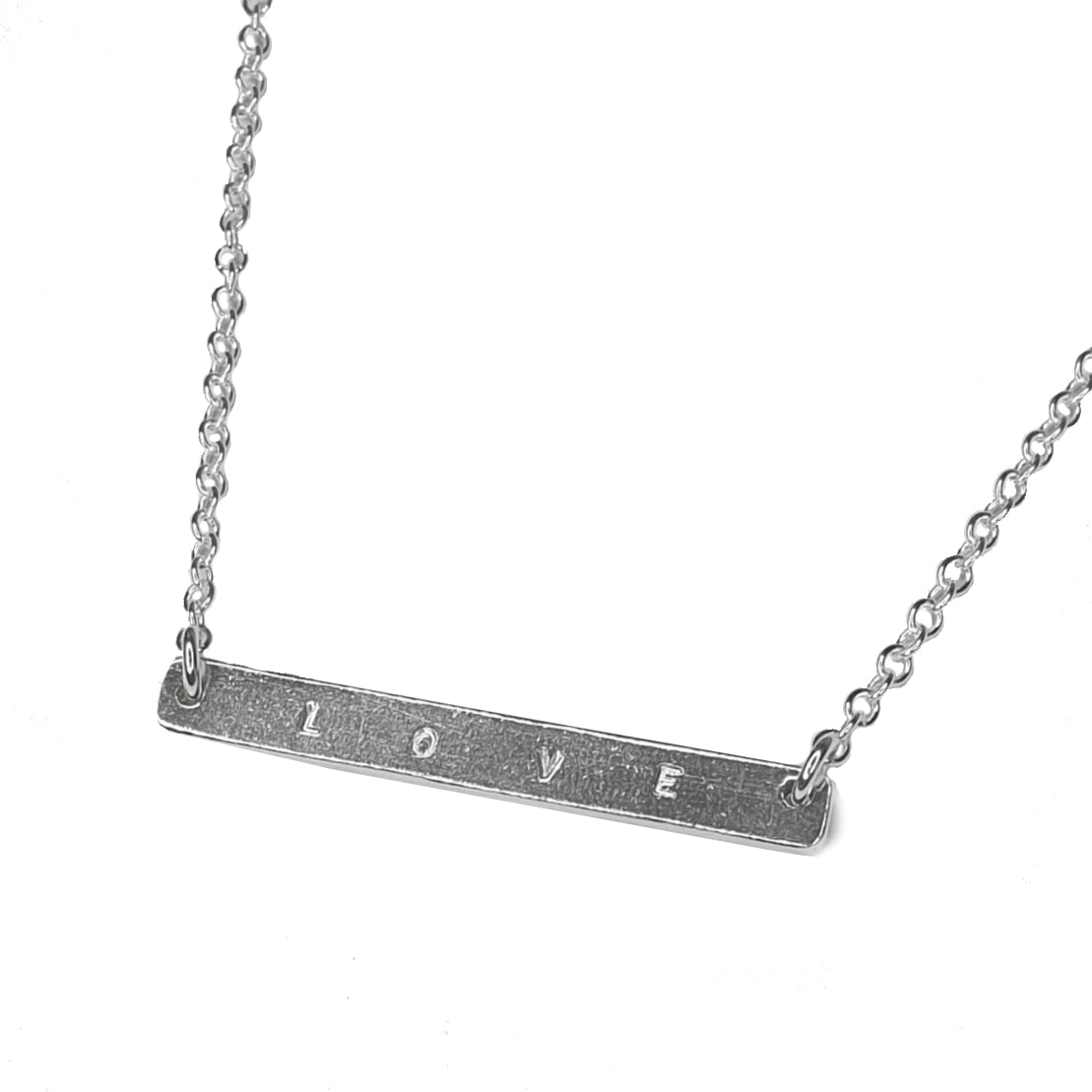 Belcher bar necklace stamped “love” on a white background 