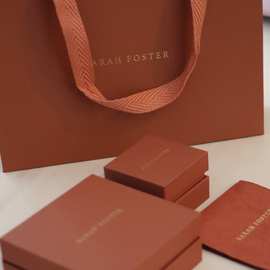 Terracotta jewelry boxes and a bag with 'Sarah Foster' branding on a light background