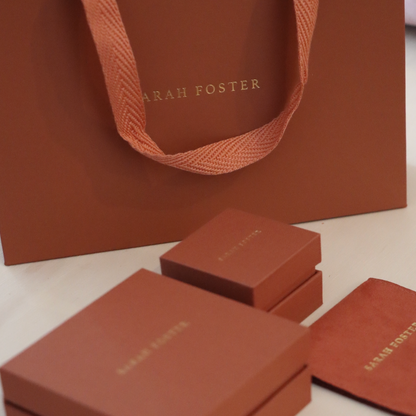Terracotta jewelry boxes and a bag with 'Sarah Foster' branding on a light background