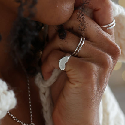 Woman with braided hair wearing a white sweater in a softly lit room wearing silver jewellery