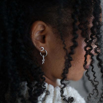 Close-up of a person with styled hair and earrings against a blurred background