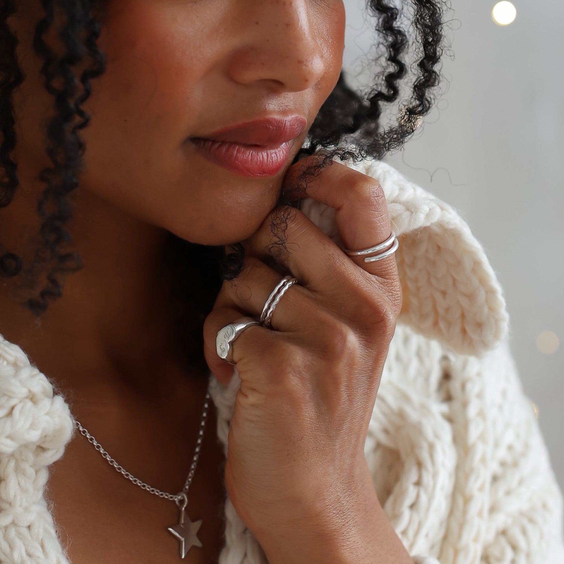 Woman wearing a white knitted sweater with a soft, blurred background