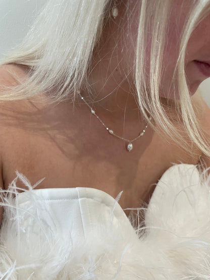 Pearl necklace worn by elika and a white feathered garment.