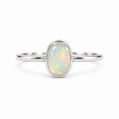 A silver ring featuring a round bezel-set iridescent opal gemstone, shown against a plain white background.