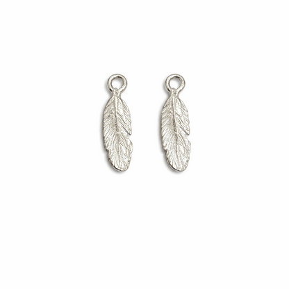 Two silver feather-shaped charms on a white background