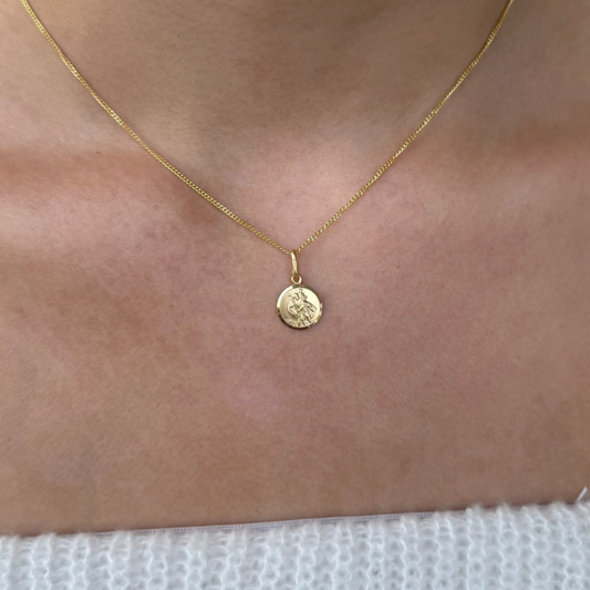 Gold plated st Christopher necklace with a round pendant on a person's neck against a white background