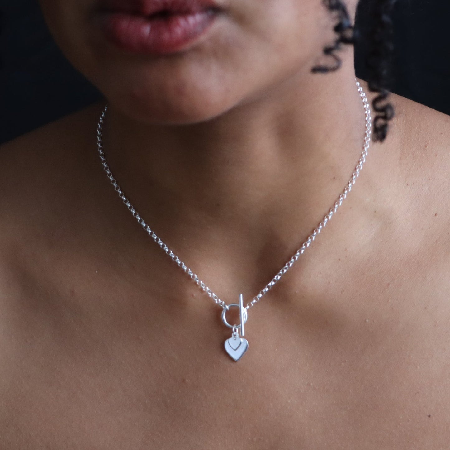 Silver necklace with a heart pendant on a person's neck