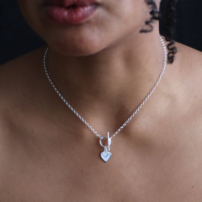 Silver necklace with a heart pendant on a person's neck