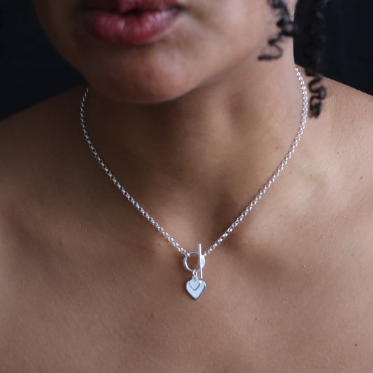 Silver necklace with a heart pendant on a person's neck