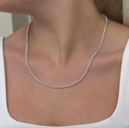 Silver belcher chain necklace on a person wearing a white top