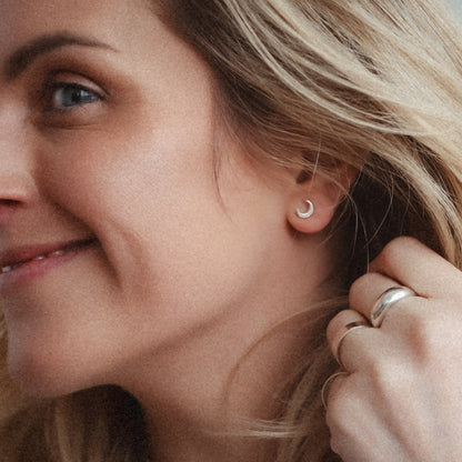 Woman adjusting an earring with a plain background
