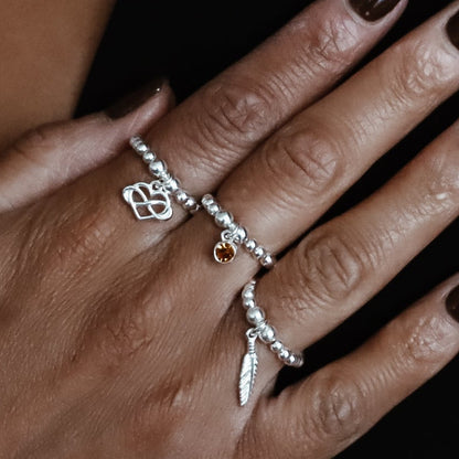 Close-up of a person's hand wearing multiple silver rings with a blurred background