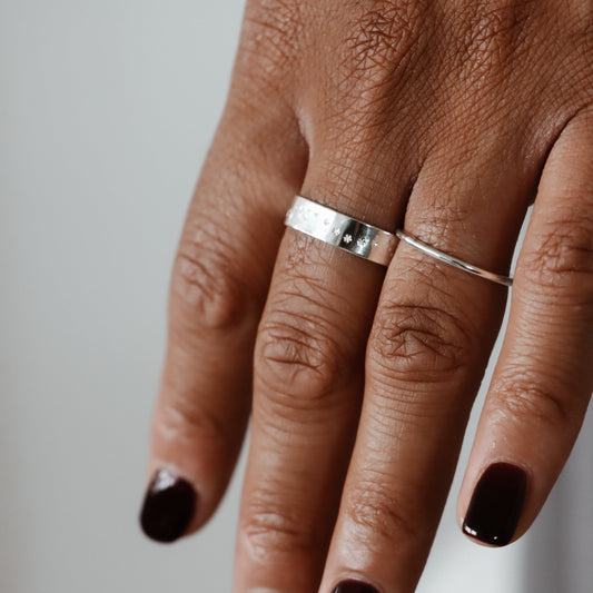 A close-up image of Leannes hand displaying a silver ring with a starry night design on their finger.