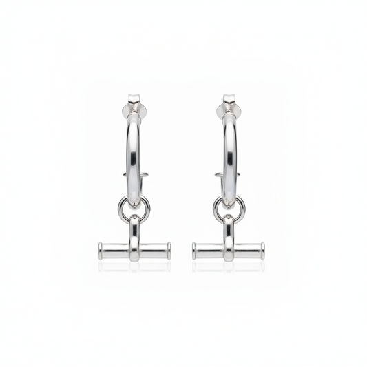 A polished silver huggie hoop earring with a dangling toggle bar charm, shown on a plain white background.
