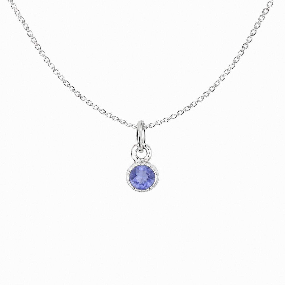 A delicate sterling silver chain necklace featuring a small round bezel-set tanzanite gemstone pendant, displayed against a clean white background.