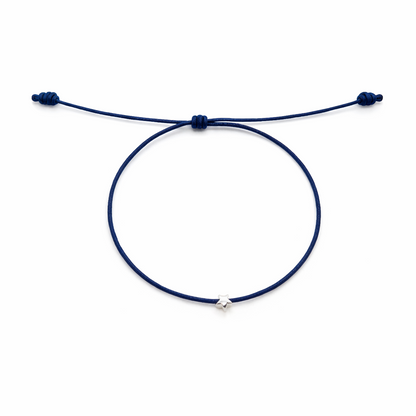 Navy blue bracelet with a small silver charm on a white background