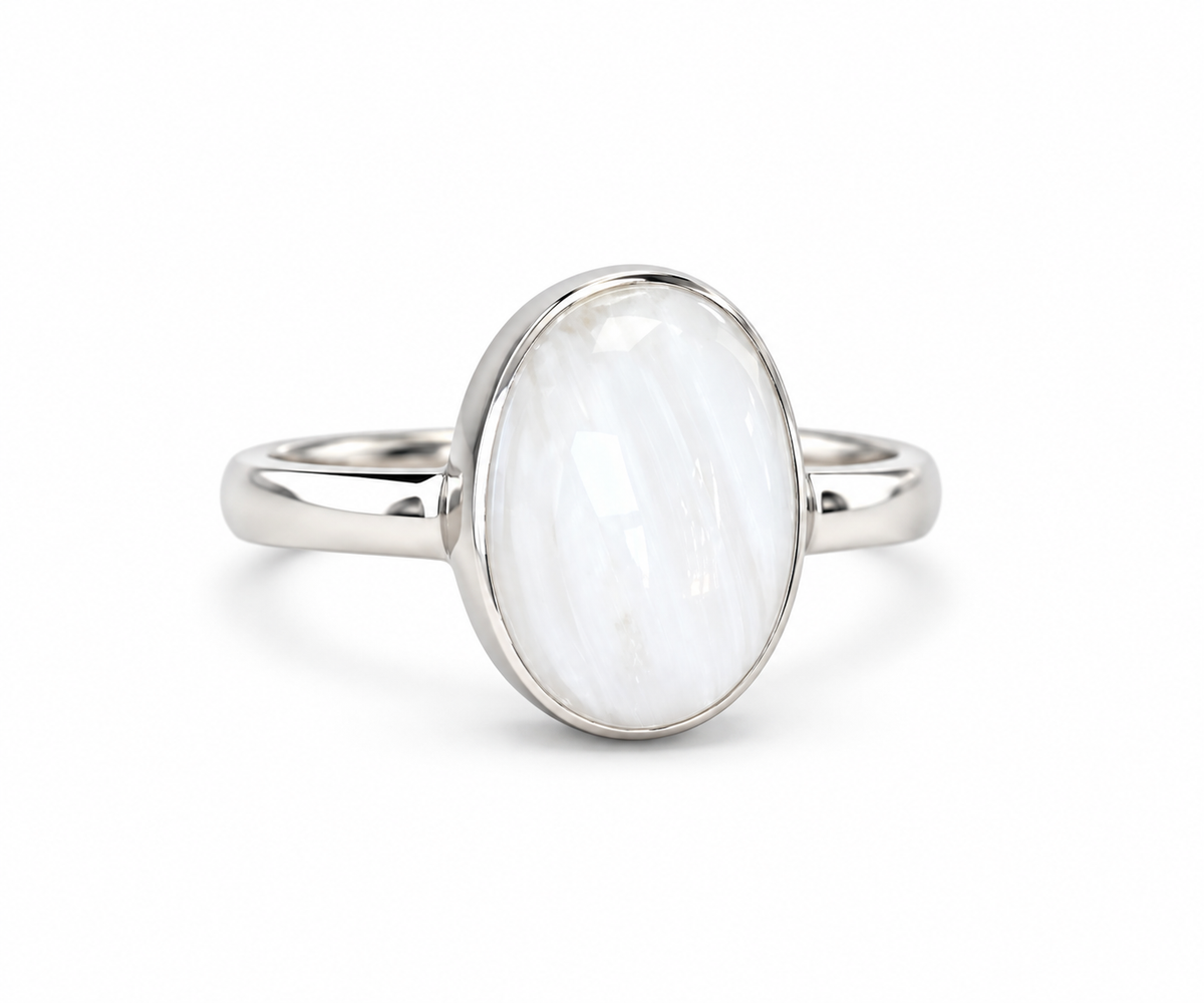 A silver ring featuring a large, oval-shaped white stone with subtle gray marbling, set in a polished silver bezel on a white background.