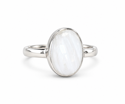 A silver ring featuring a large, oval-shaped white stone with subtle gray marbling, set in a polished silver bezel on a white background.