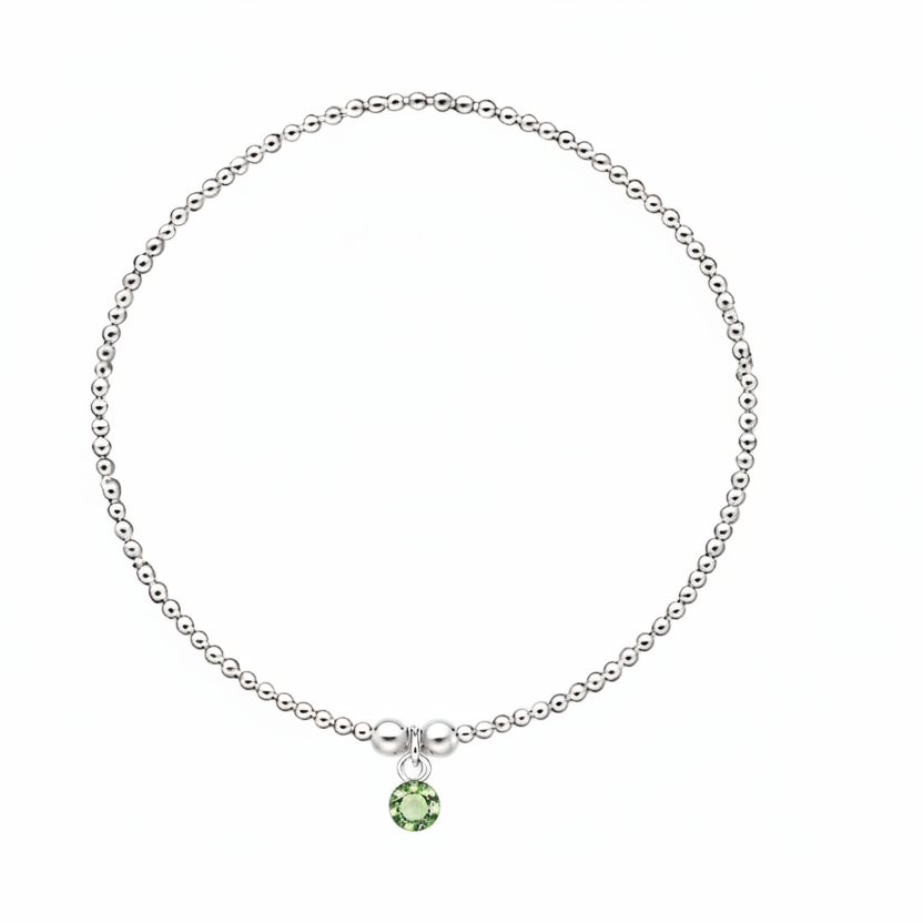 A delicate silver beaded bracelet with a small green gemstone pendant, displayed on a clean white background.