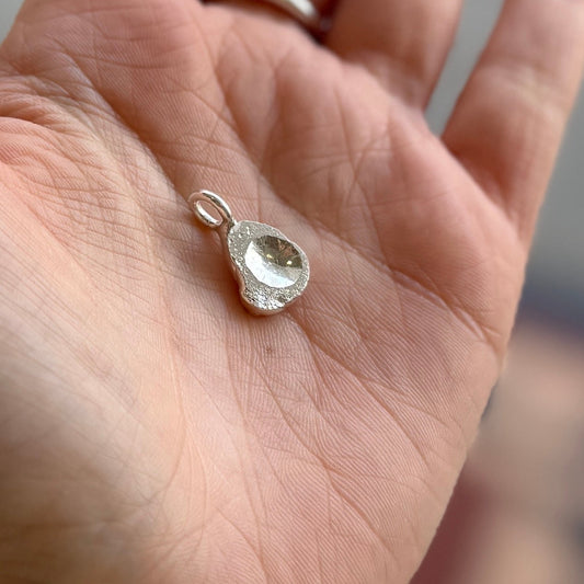 Silver teardrop-shaped pendant on a hand
