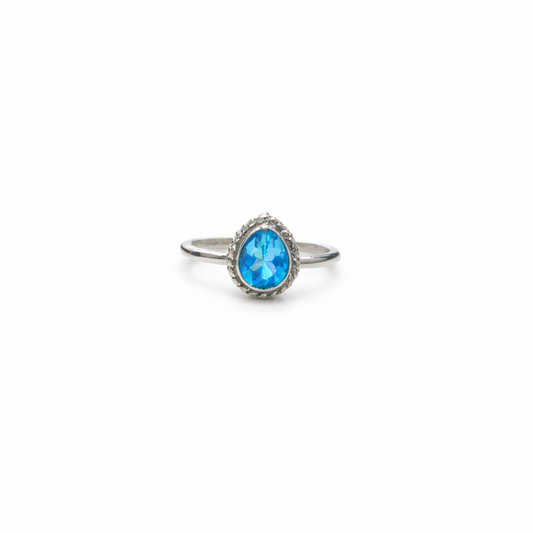 Silver ring with a blue topaz gemstone on a white background