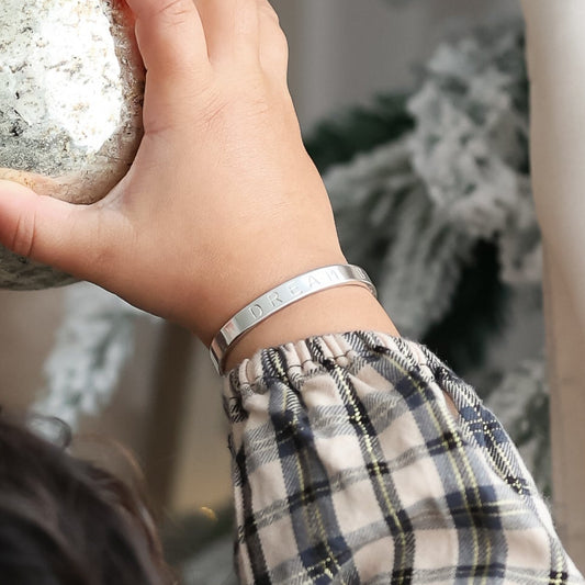 Person holding a decorative ornament in front of a Christmas tree.