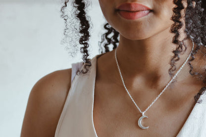 Sterling silver crescent moon pendant on a fine chain, worn by a model in a white top