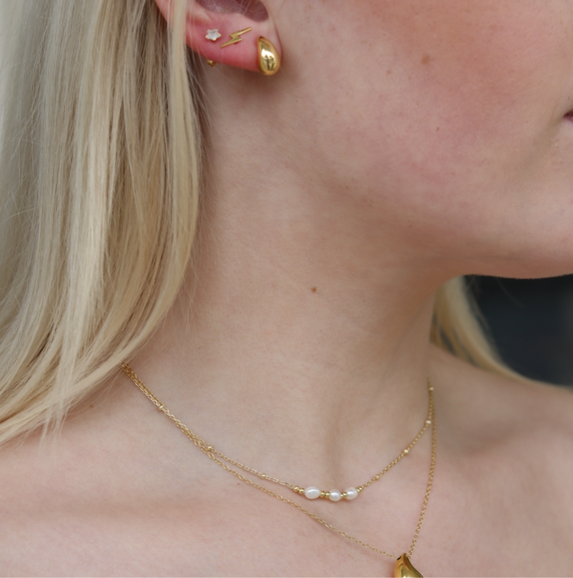 a close up of a gold plated pearl necklace on a model 