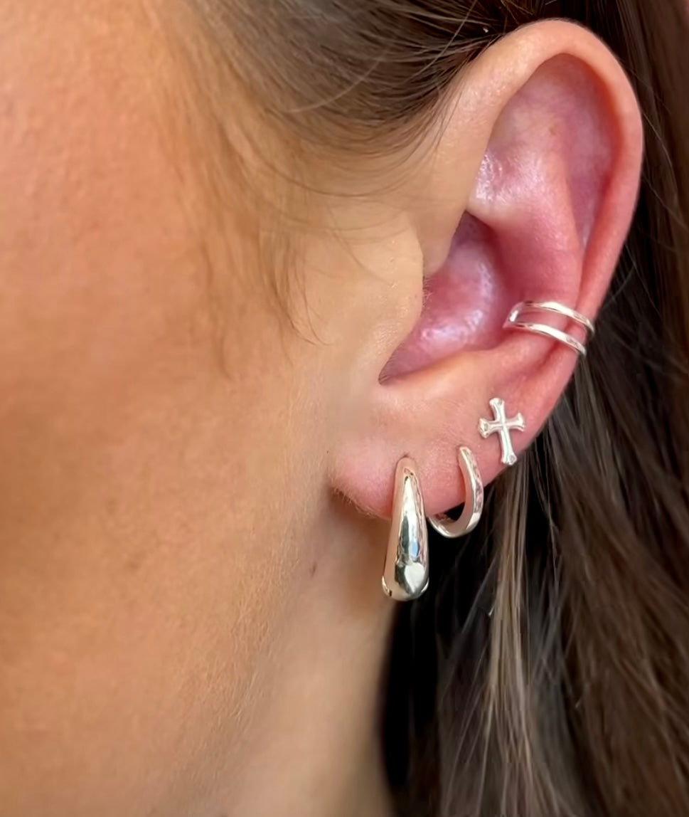 Close-up of an ear with multiple silver earrings