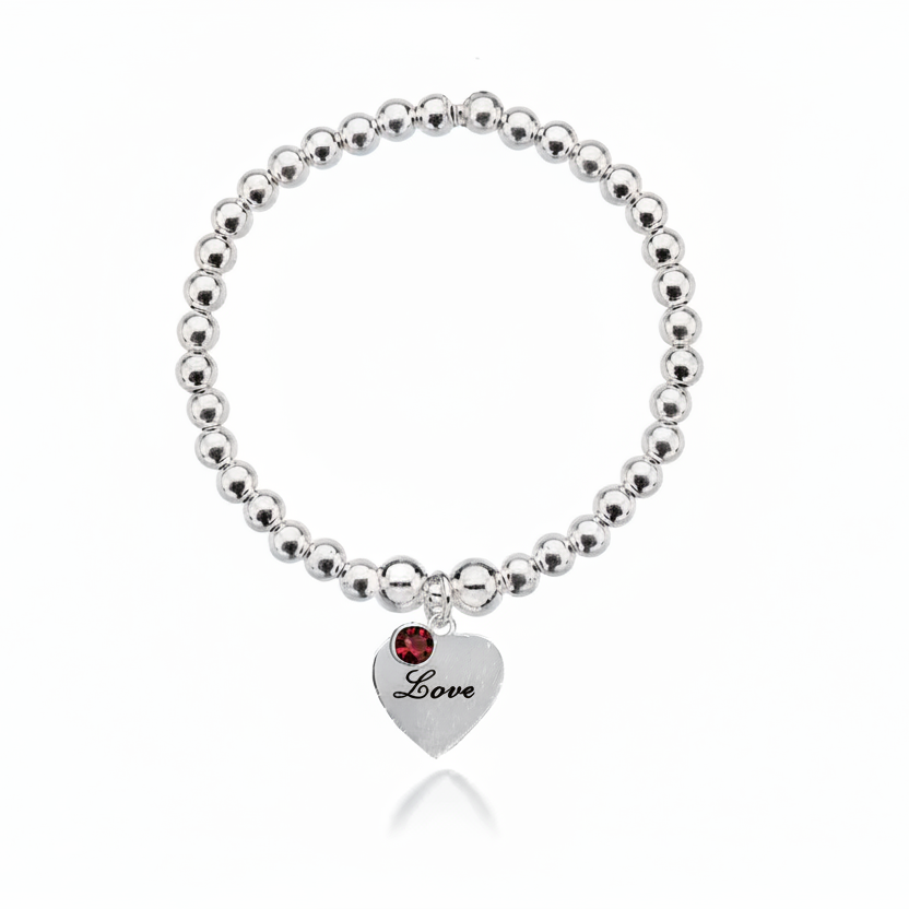 Silver beaded bracelet with a heart-shaped tag and red gemstone on a white background