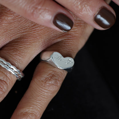 Close-up of hands with dark nail polish and multiple rings on a blurred background