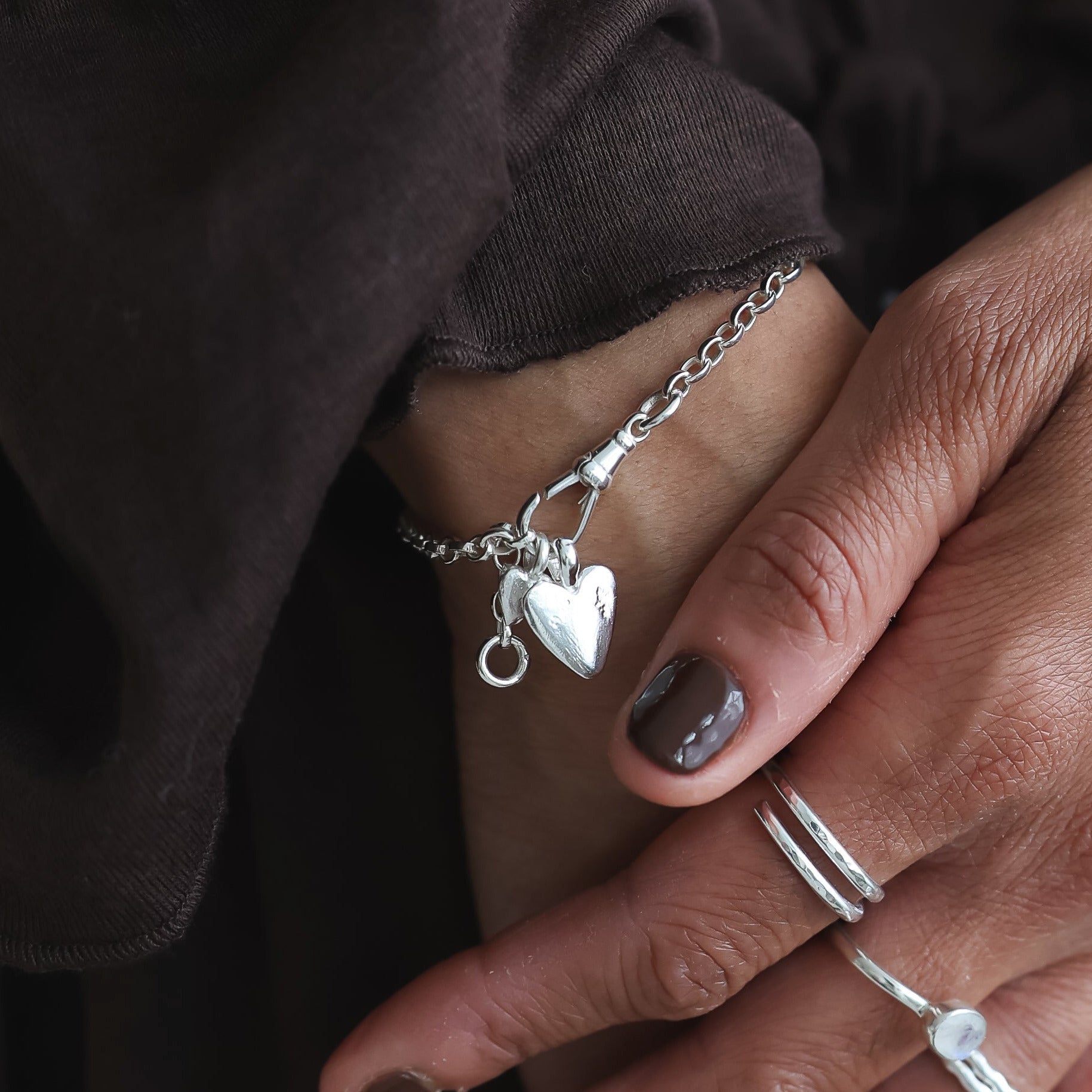 Close-up of hands with jewelry wearing a dark brown garment.