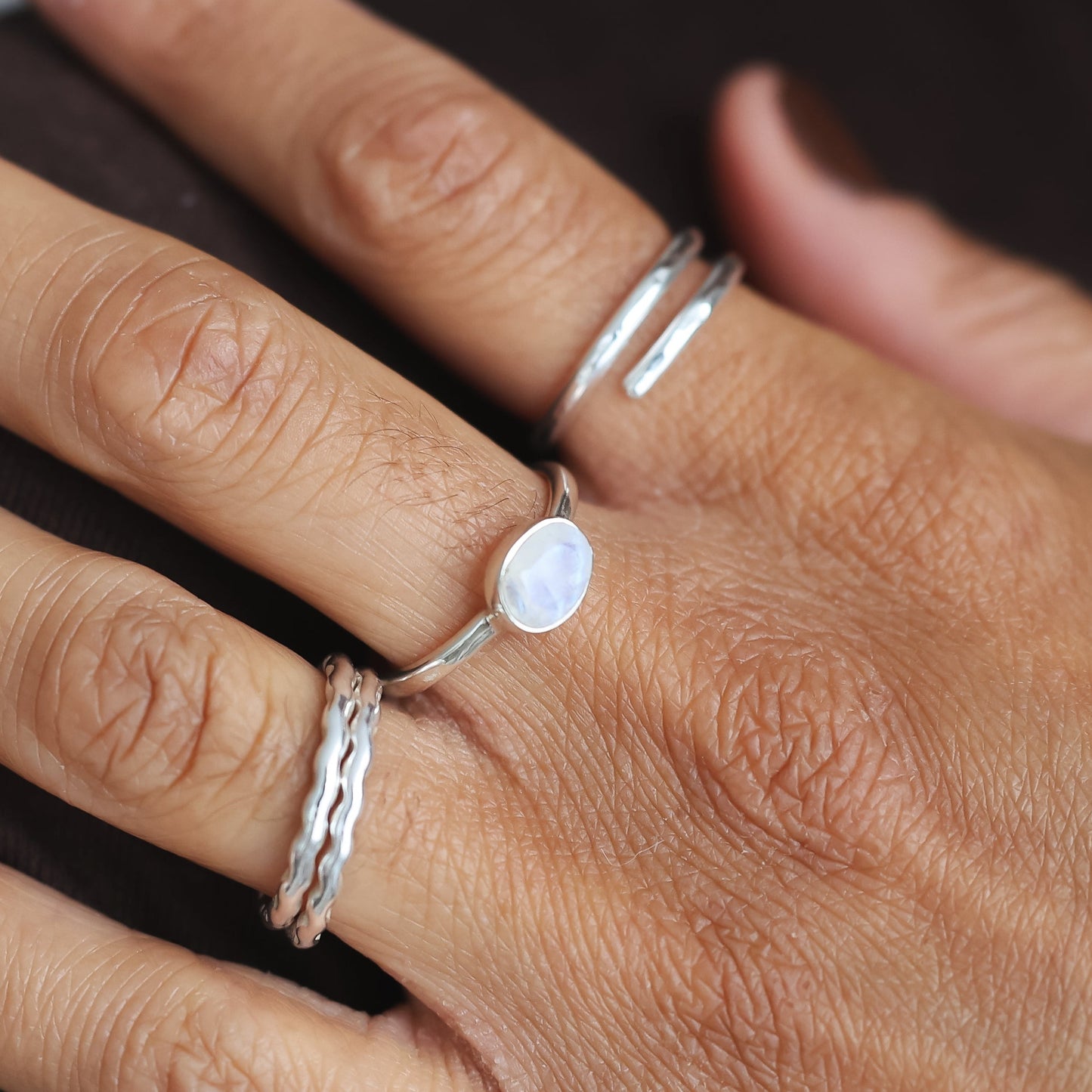 Close-up of a hand wearing multiple rings with a blurred background