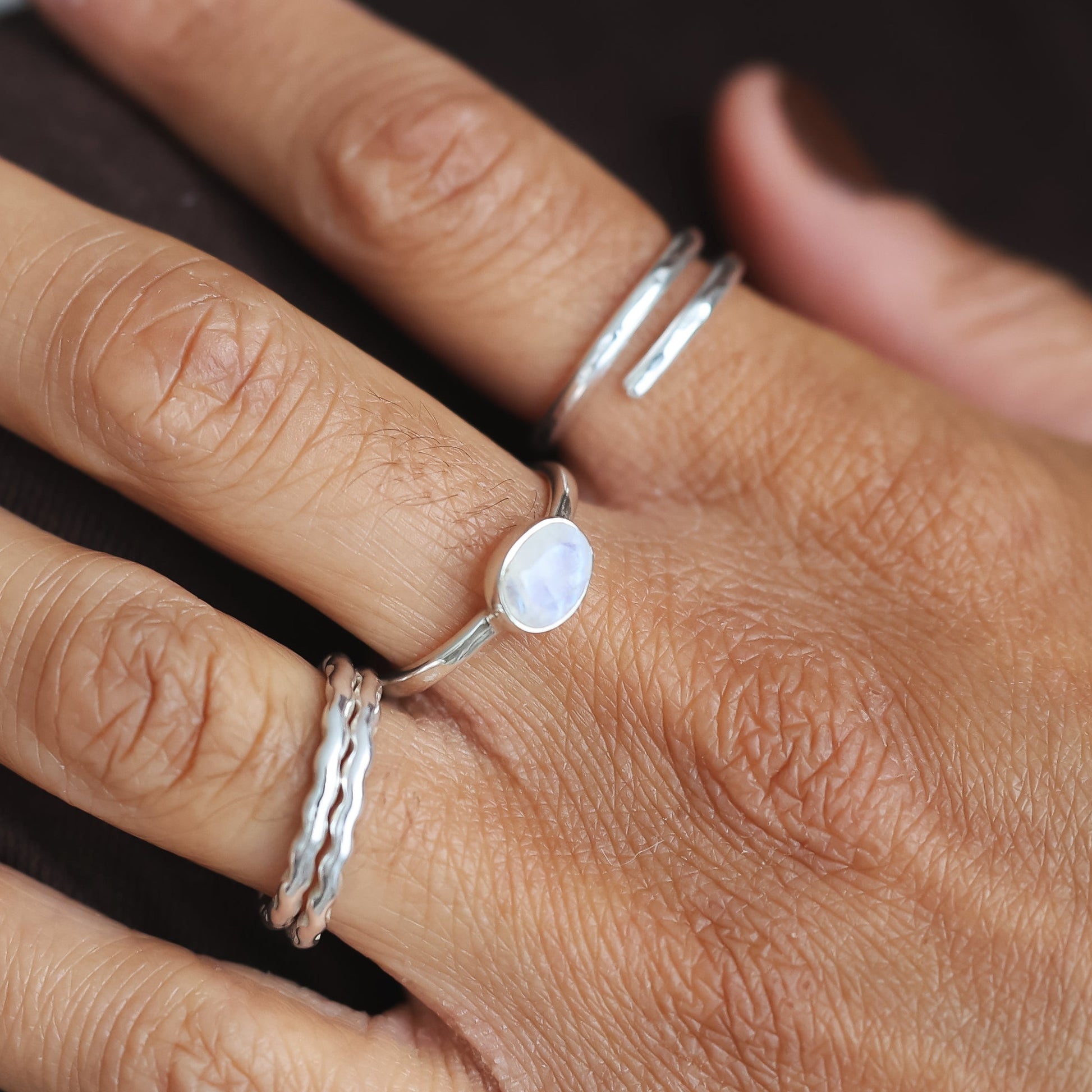 Close-up of a hand wearing multiple rings with a blurred background
