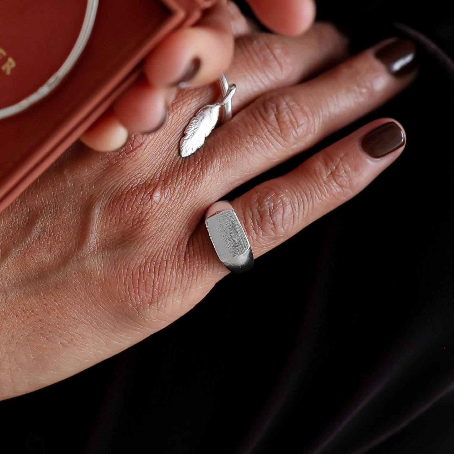 Person holding a silver bracelet in a red box with 'Sarah Foster' branding.