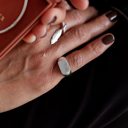 Person holding a silver bracelet in a red box with 'Sarah Foster' branding.