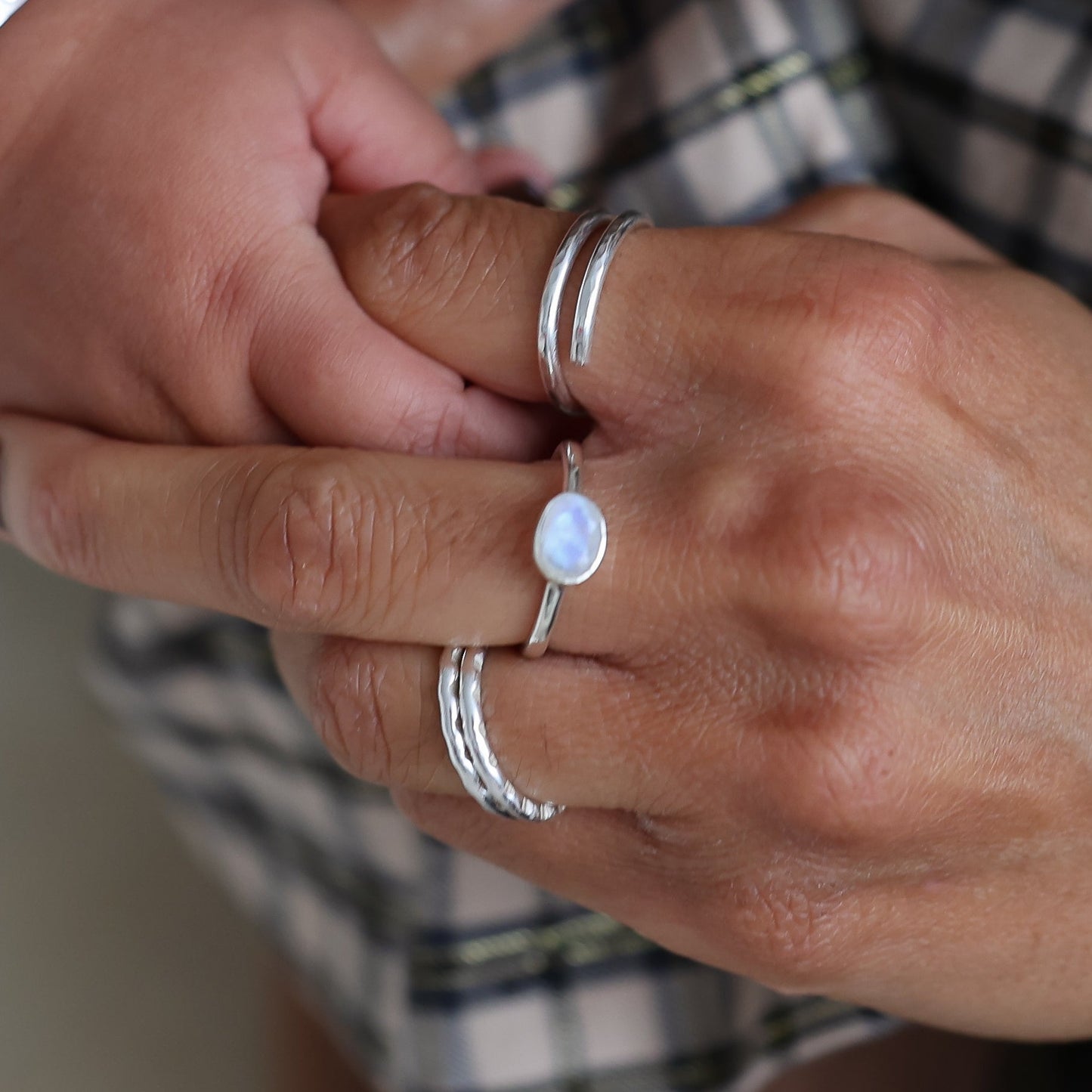 Close-up of two hands holding each other, wearing silver rings and bracelets.
