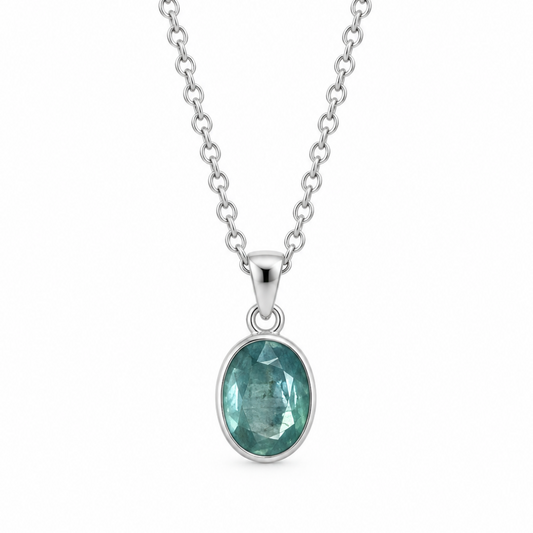 A silver chain necklace with an oval bezel-set green kyanite gemstone pendant, shown against a plain white background.
