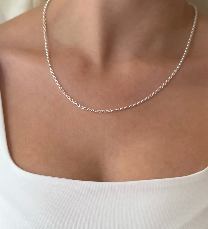 Silver belcher chain necklace on a person wearing a white top