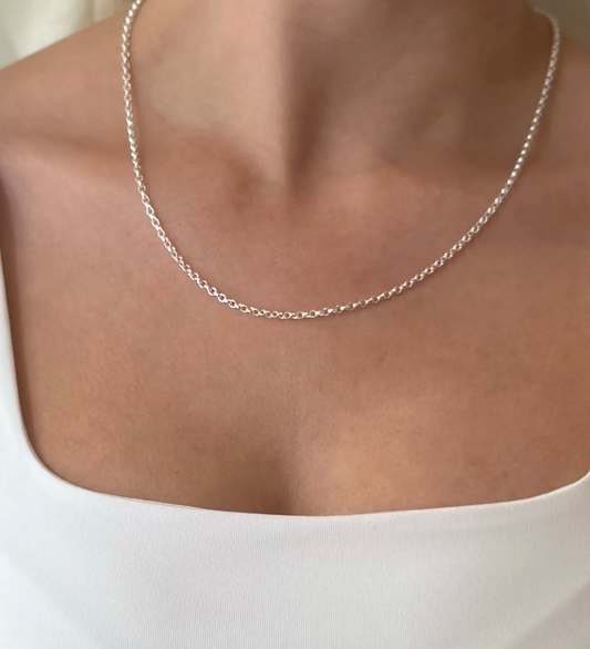Silver belcher chain necklace on a person wearing a white top