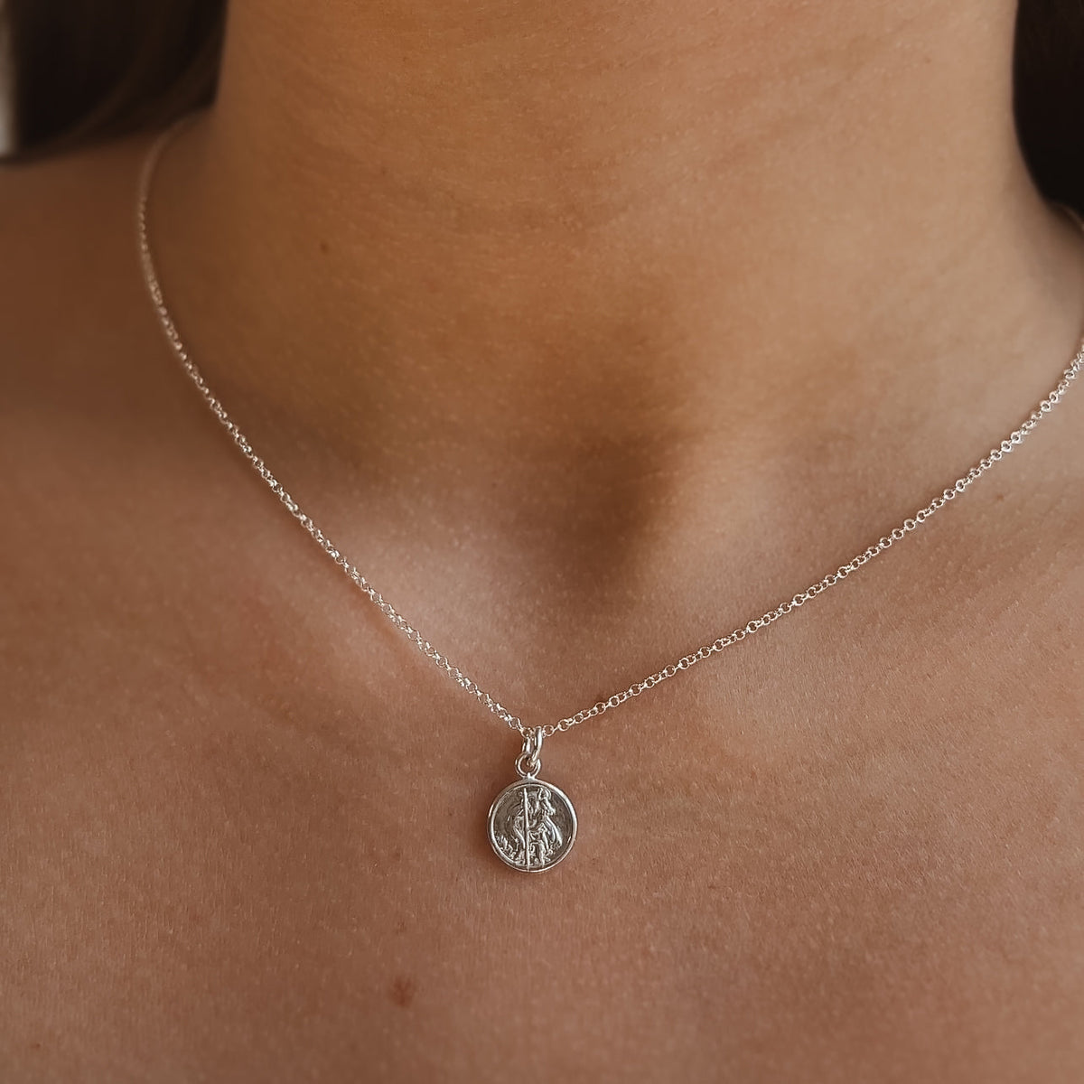 Silver necklace with ast christopher  pendant on a person's neck
