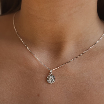 Silver necklace with ast christopher  pendant on a person's neck