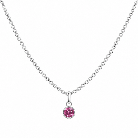 A delicate silver chain necklace with a small round bezel-set pink gemstone pendant, displayed against a solid white background.