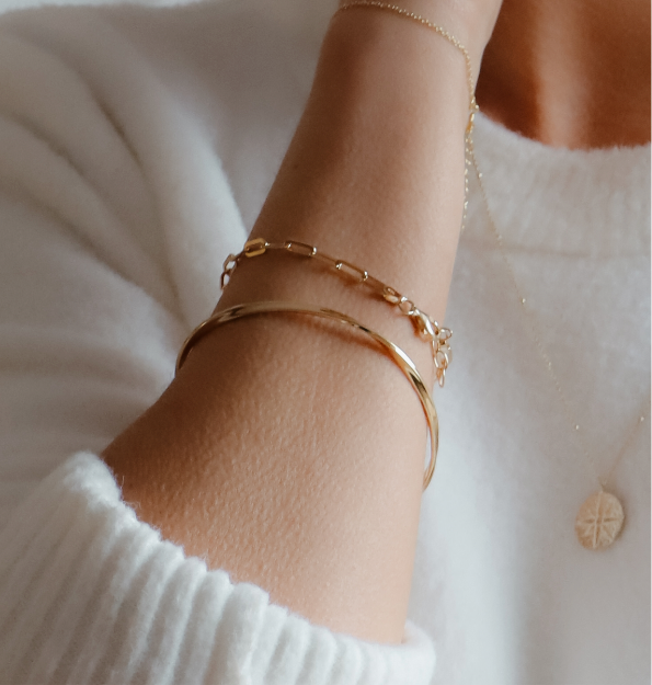18ct gold-plated paper clip chain bracelet worn on a wrist alongside a gold-coloured bangle
