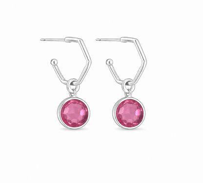 a pair of silver hoops featruing round pink tourmaline charms. On a white background
