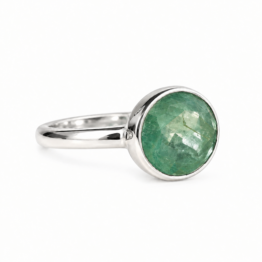 A silver ring featuring a round, faceted green kyanite gemstone in a bezel setting, shown on a clean white background.
