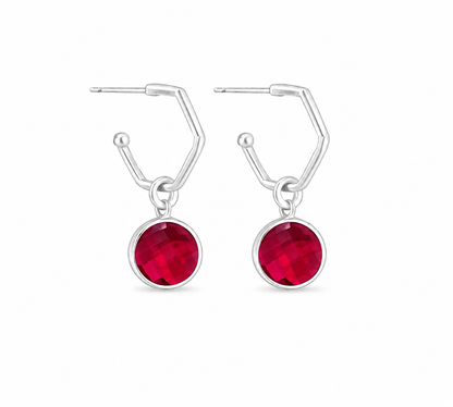 A pair of silver drop earrings featuring a round ruby charms on a plain white background.