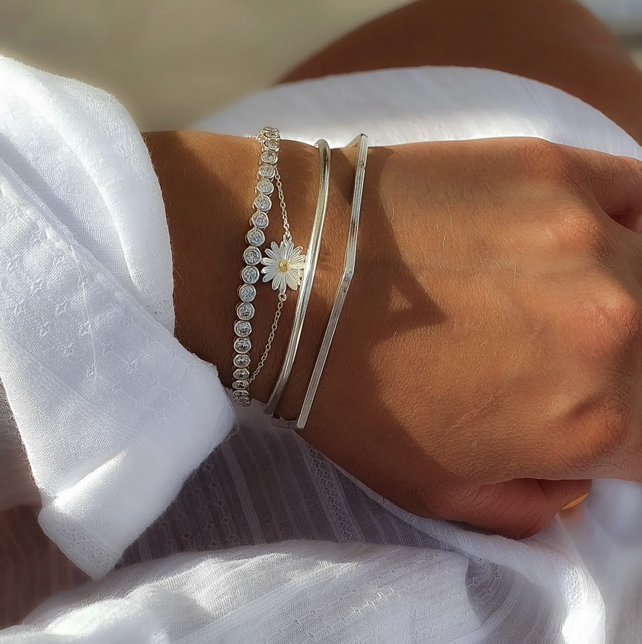 Sterling silver Polished Stacking Bangle worn with another silver bangle, a daisy bracelet and a stone-set bracelet