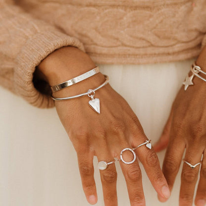 teeny heart dangle ring stacked with other rings on a model 