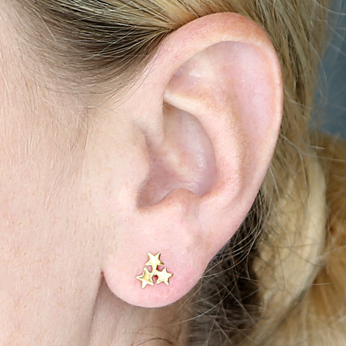18ct gold-plated stud earring with three clustered stars, worn on an ear